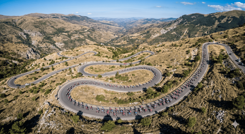 Ciclisti professionisti in salita durante la quarta tappa del Giro d'Italia 2026 verso Cosenza.