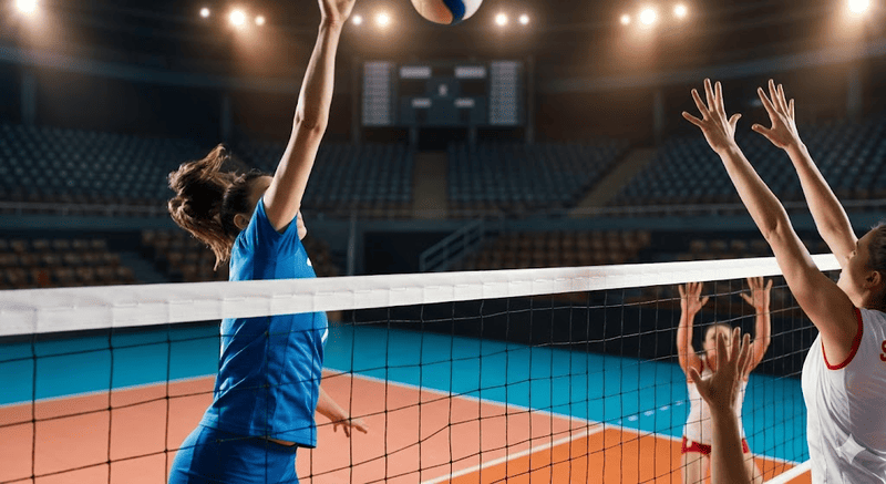 Dettaglio ravvicinato della rete da pallavolo e del mondoflex in un palazzetto dello sport illuminato dai riflettori, con sfondo sfocato.